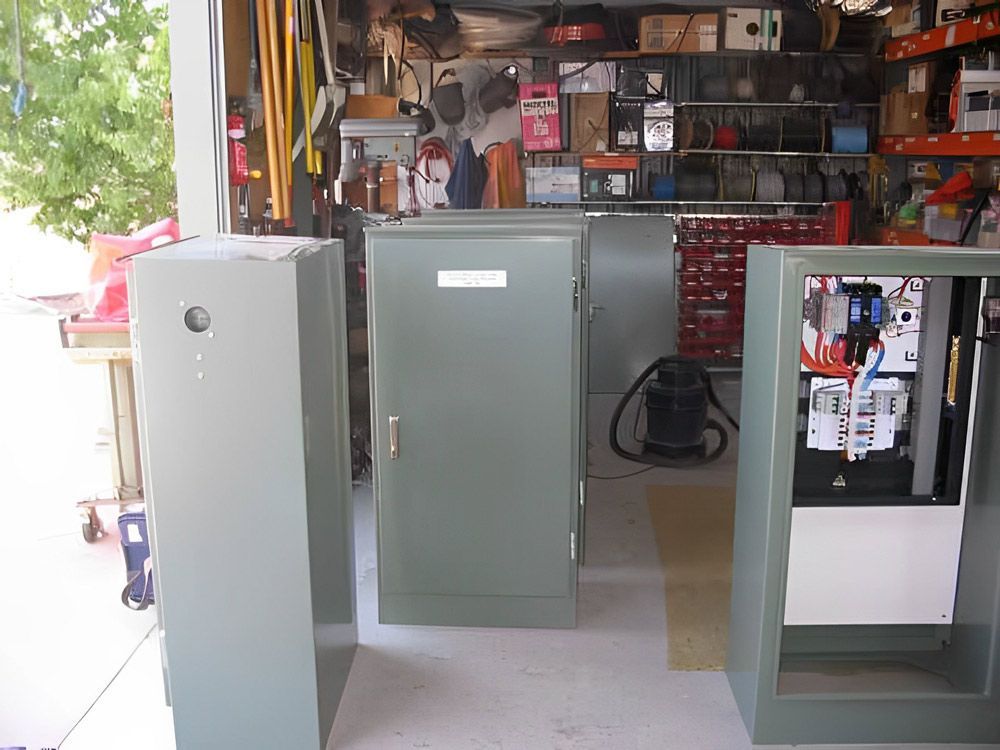Two grey electrical distribution cabinets standing in a workshop store area.