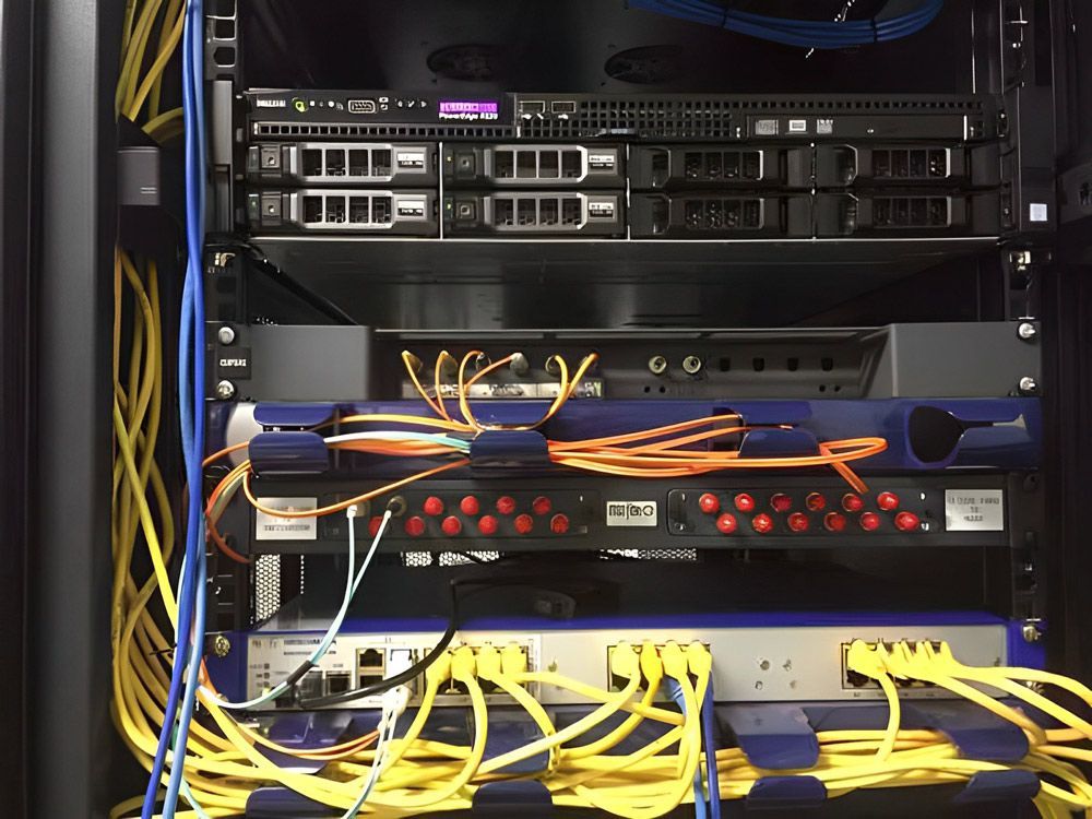 Server rack with network switches and orange and yellow patch cabling.