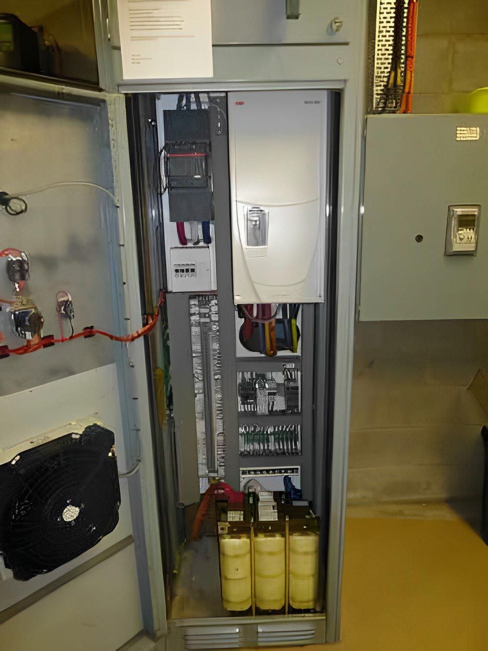 Open electrical switchboard cabinet showing wiring and yellow circuit breakers.